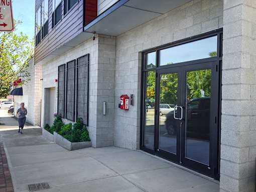 Modern building entrance with glass doors and concrete facade at 68 Beale Apartments, Quincy